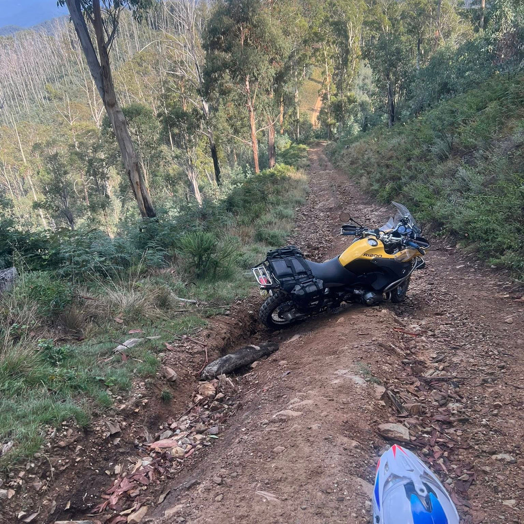 Nomad Moto Adjustable Rackless Motorcycle on a dirt trail with trees and mountains in the background